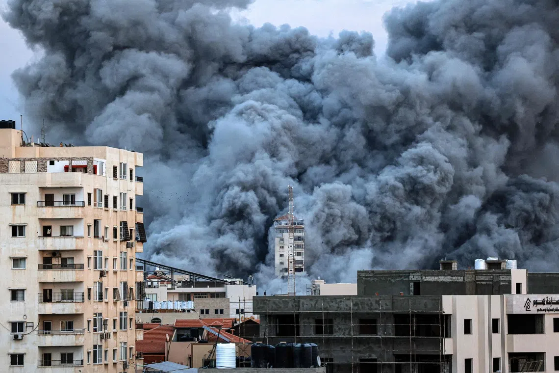 A plume of smoke rises above buildings in Gaza City on October 7, 2023 during an Israeli air strike that hit the Palestine Tower building.