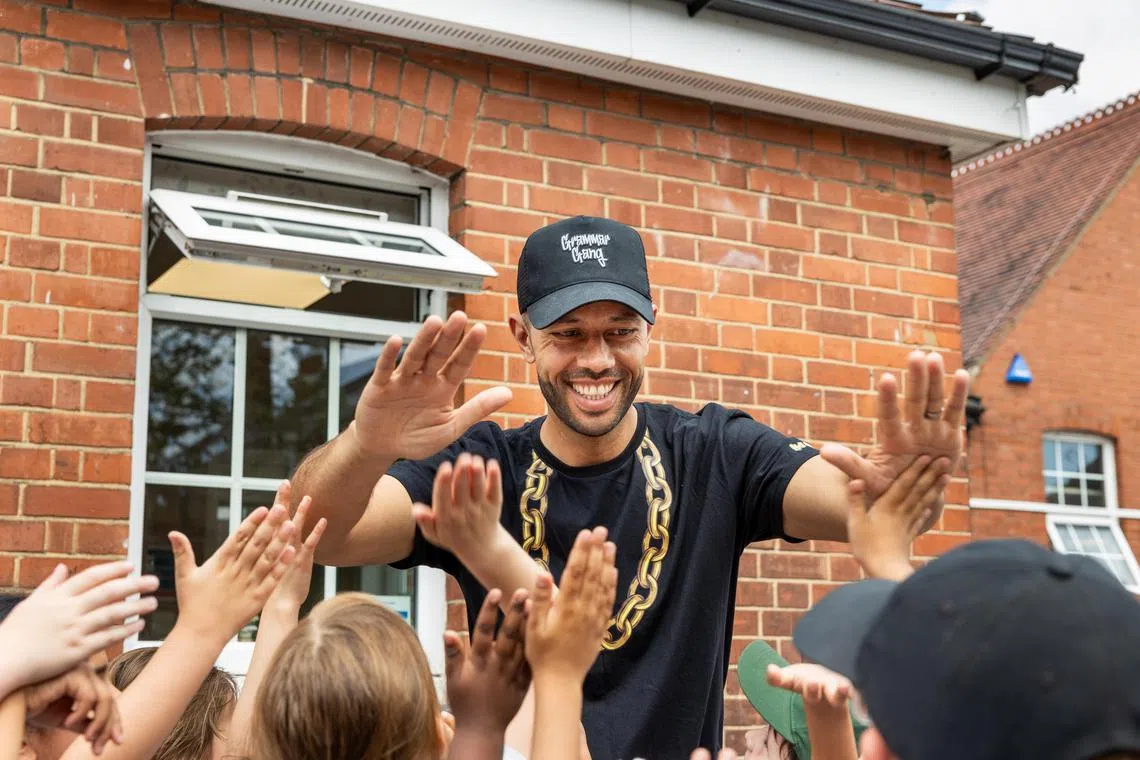 Jacob Mitchell with young fans at Foulds School, his alma mater, in High Barnet, England, on June 24, 2024. Under the name of his alter ego, MC Grammar, Mitchell has become a wildly popular performer whose rhymes have made reading and grammar all the rage among young people across Britain. (Jeremie Souteyrat/The New York Times)