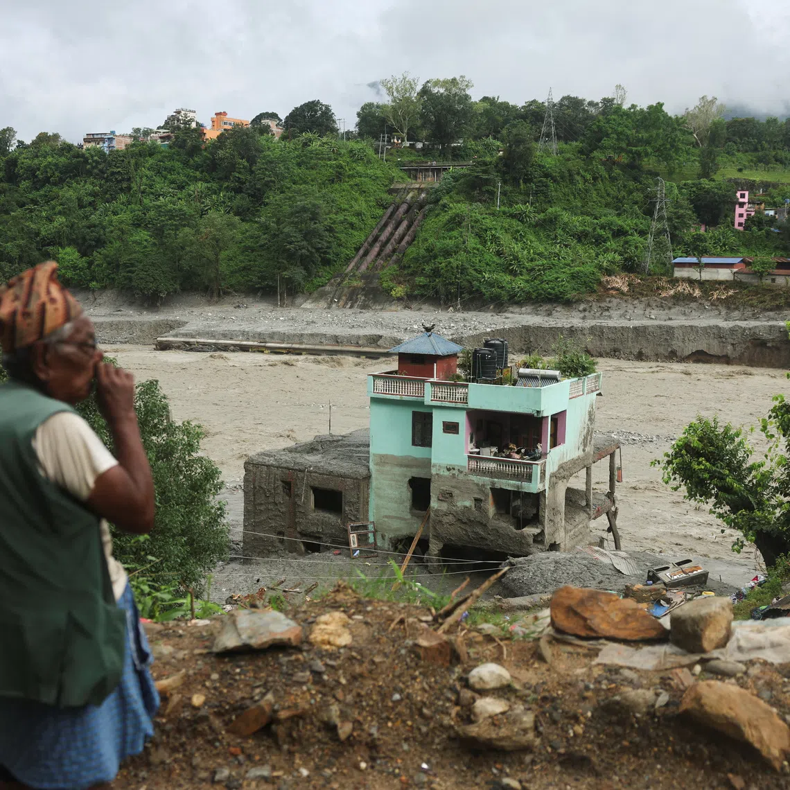 A man looks at the "green miracle house" as it stands amid debris after surviving flash floods and a mudslide in Trishuli, Nuwakot district, Nepal, September 1, 2026. REUTERS/Francis Mascarenhas