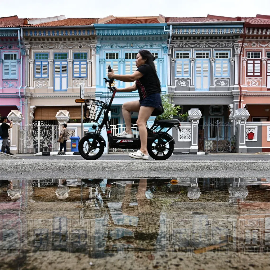 A woman cycling past shophouses in Koon Seng Road in Katong, 12 April 2024. Peranakan shophouses in Katong and Joo Chiat provide a glimpse of Singapore’s past.