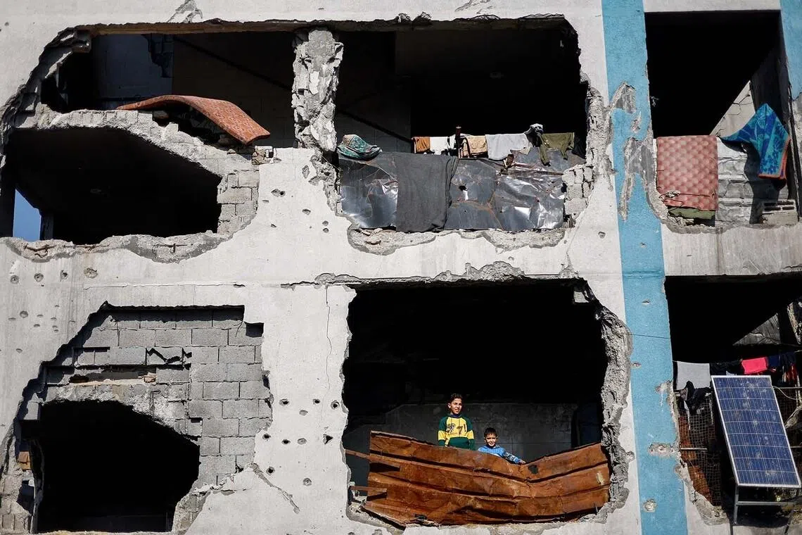Palestinians look out from a building destroyed during the war, in Jabalia, northern Gaza Strip, January 6, 2026. REUTERS/Mahmoud Issa TPX IMAGES OF THE DAY