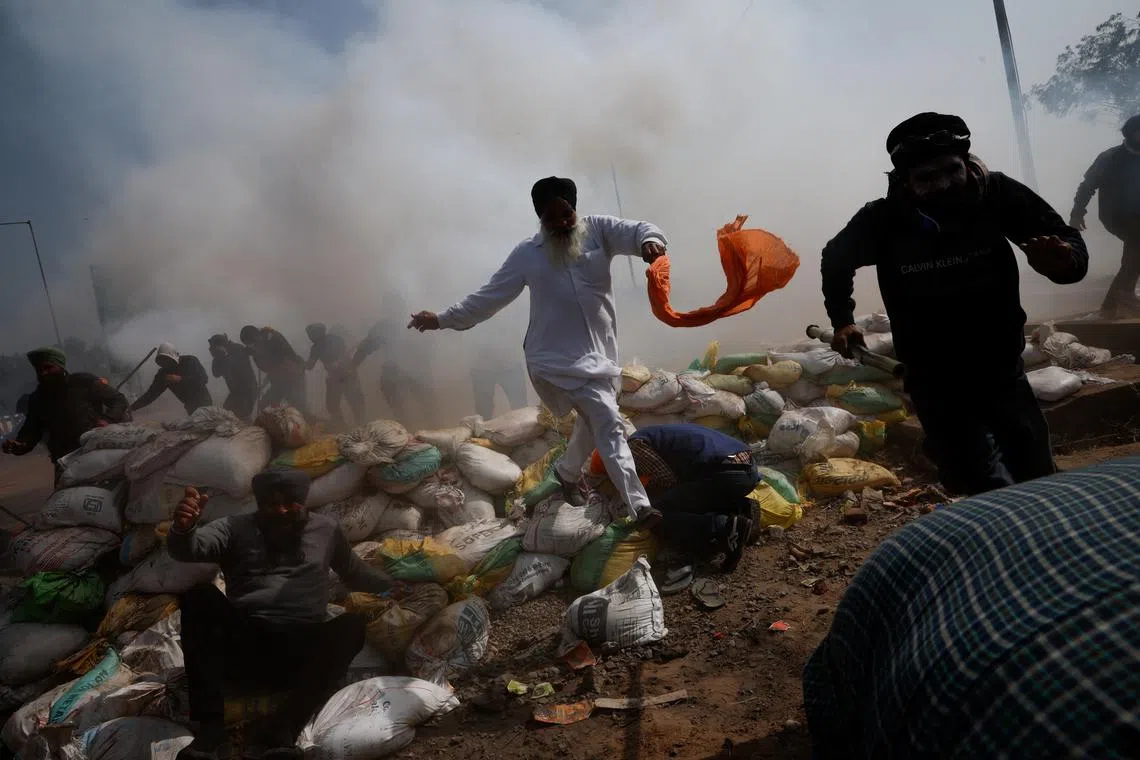 Farmers, who are marching towards New Delhi to press for better crop prices promised to them in 2021, run for cover amidst tear gas fired by police to disperse them at Shambhu barrier, a border crossing between Punjab and Haryana states, India, February 21, 2024. REUTERS/Adnan Abidi
