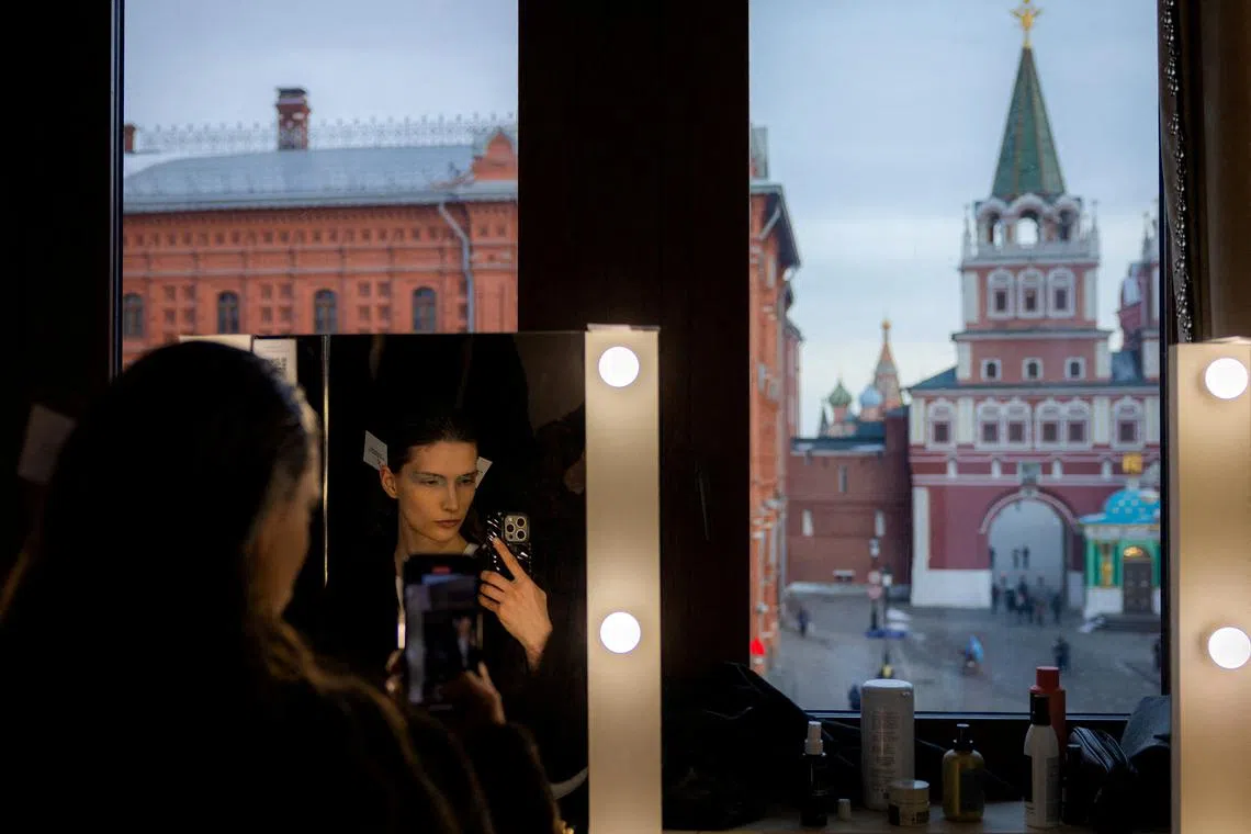 A model using her smartphone backstage during the Ruban fashion show with Saint Basil's Cathedral and Voskresenskie (Resurrection) Gates seen in the background, in Moscow, Russia, on Mar 17, 2025.