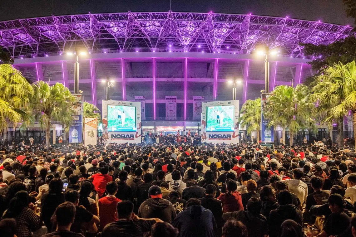 Indonesian football fans watch their team's match on screens outside the Gelora Bung Karno stadium in Jakarta.