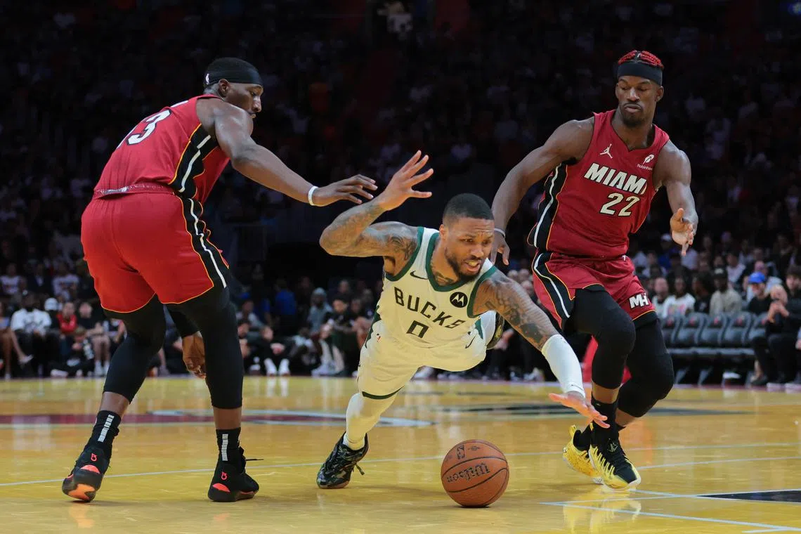 Milwaukee Bucks guard Damian Lillard dives for the ball against Miami Heat centre Bam Adebayo and forward Jimmy Butler during the third quarter at Kaseya Centre.