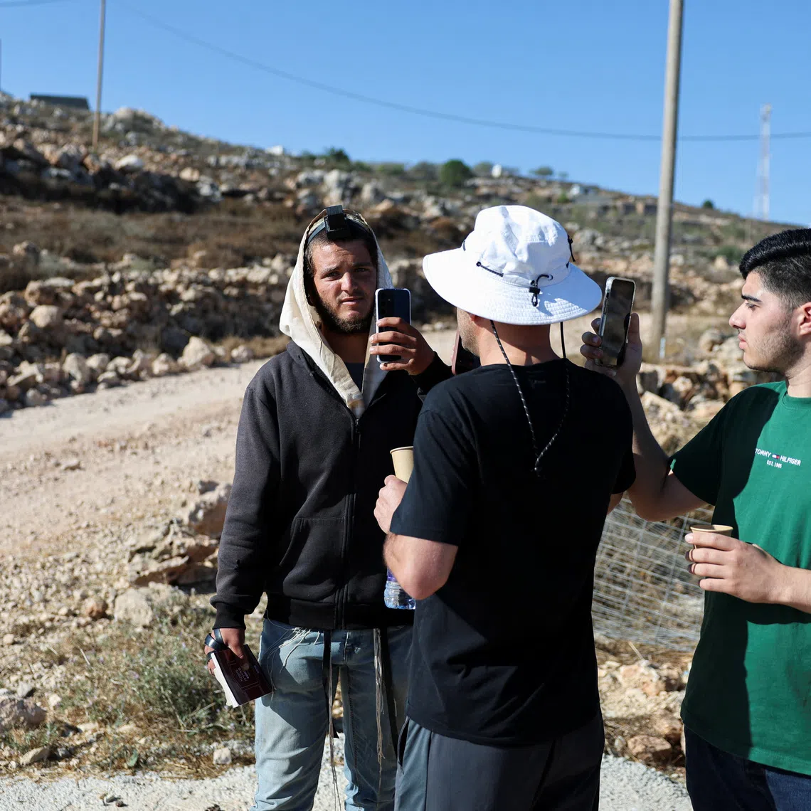 Palestinian-American Loui Ridi and his nephew Ahmed (R), whose house has been encircled by militant settlers for over a week, films an Israeli settler (L) who entered his property in Qusra, Israeli-occupied West Bank, August 18, 2026. REUTERS/Ammar Awad