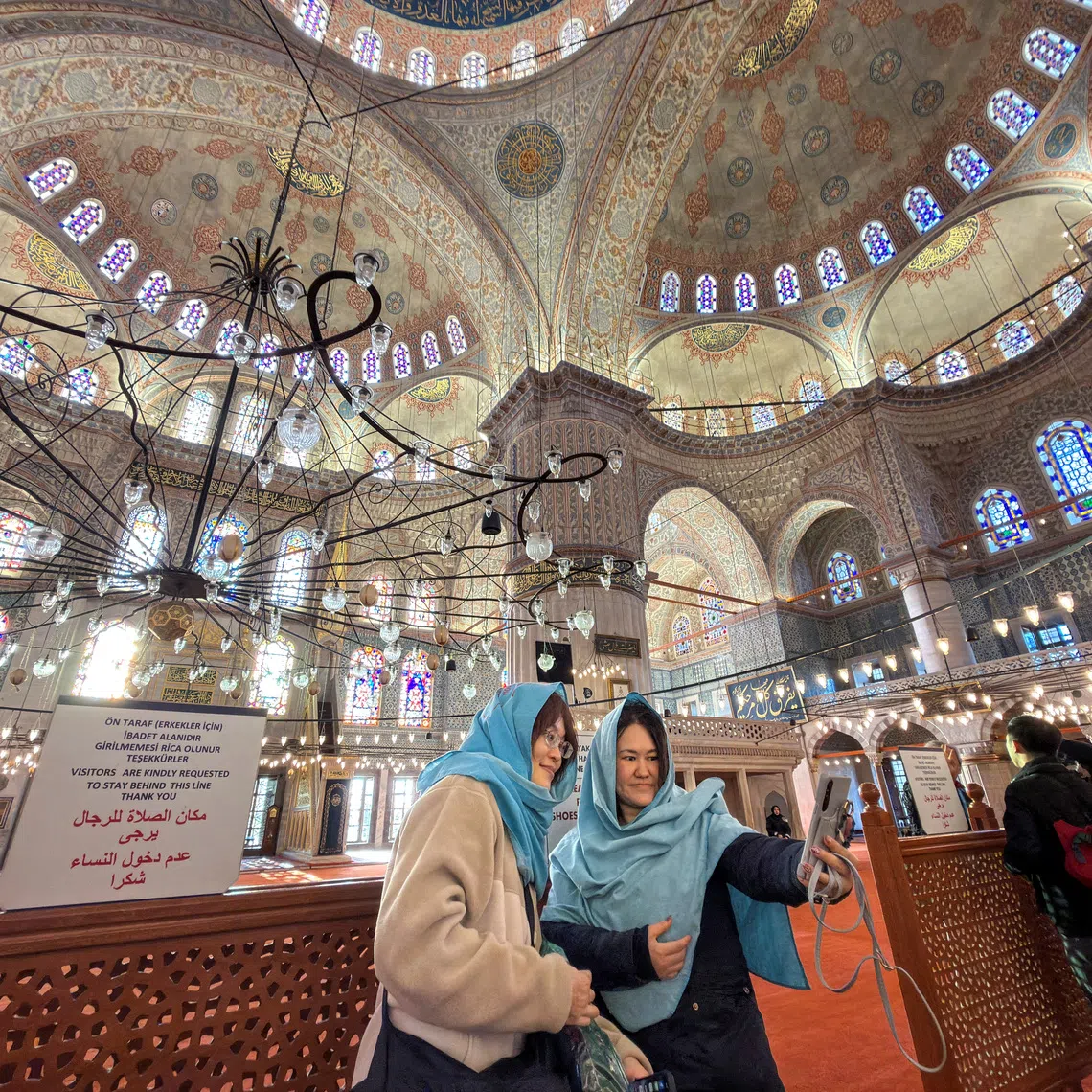 Japanese tourists pose for a selfie as they visit Ottoman-era Sultanahmet Mosque, known as the Blue Mosque, which Pope Leo XIV is expected to visit later this week, in Istanbul, Turkey, November 25, 2025. REUTERS/Murad Sezer
