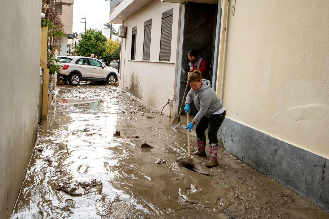 A woman cleans mud off a street following floods caused by storm Bora in the area of Lalysos, on the island of Rhodes, Greece, December 1, 2024. REUTERS/Lefteris Damianidis