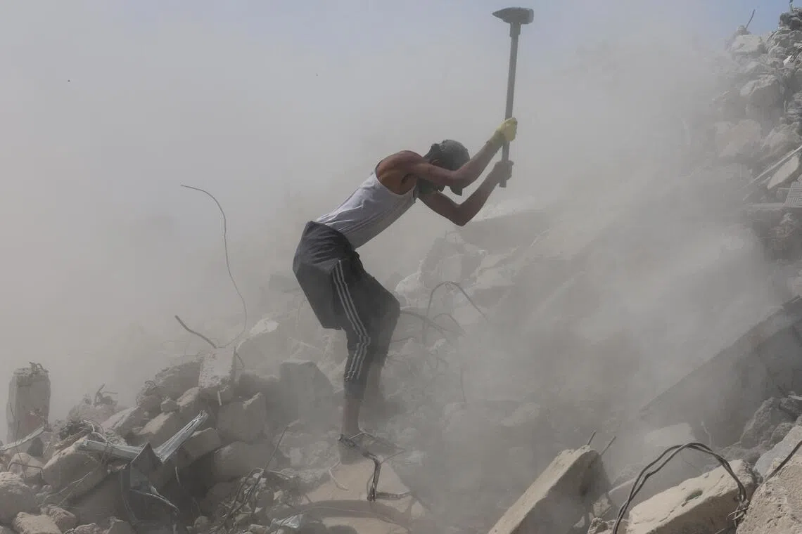 A Palestinian worker breaks up concrete while working on rubble in Khan Younis, southern Gaza Strip, on April 19.