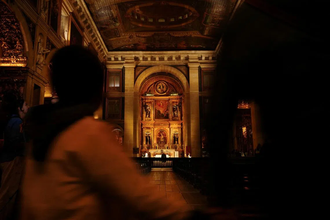 A child passes by while holding an adult hand inside a church in Lisbon, Portugal, April 10, 2024. REUTERS/Pedro Nunes