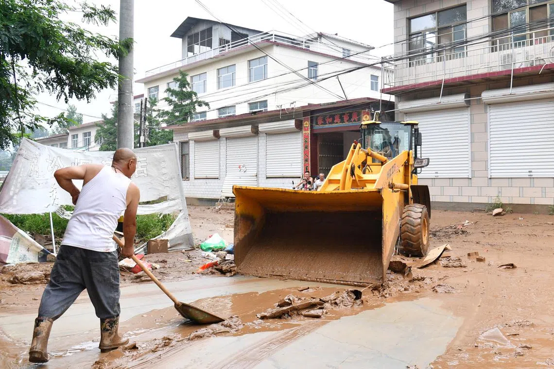 FILE PHOTO: Villagers clear the mud from a street after heavy rainfall flooded Yi county of Baoding, Hebei province, China July 26, 2025. cnsphoto via REUTERS/File Photo