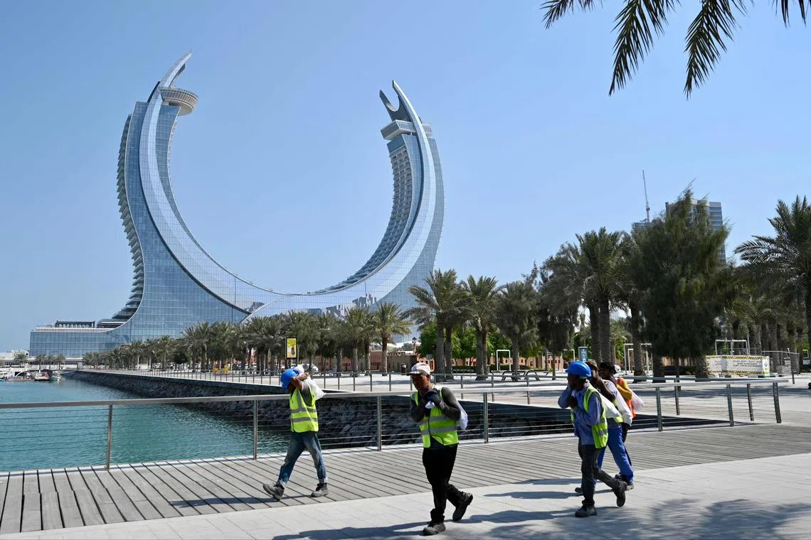 Workers walk along the marina near the Katara Towers in the Qatari coastal city of Lusail on Oct 23, 2022.