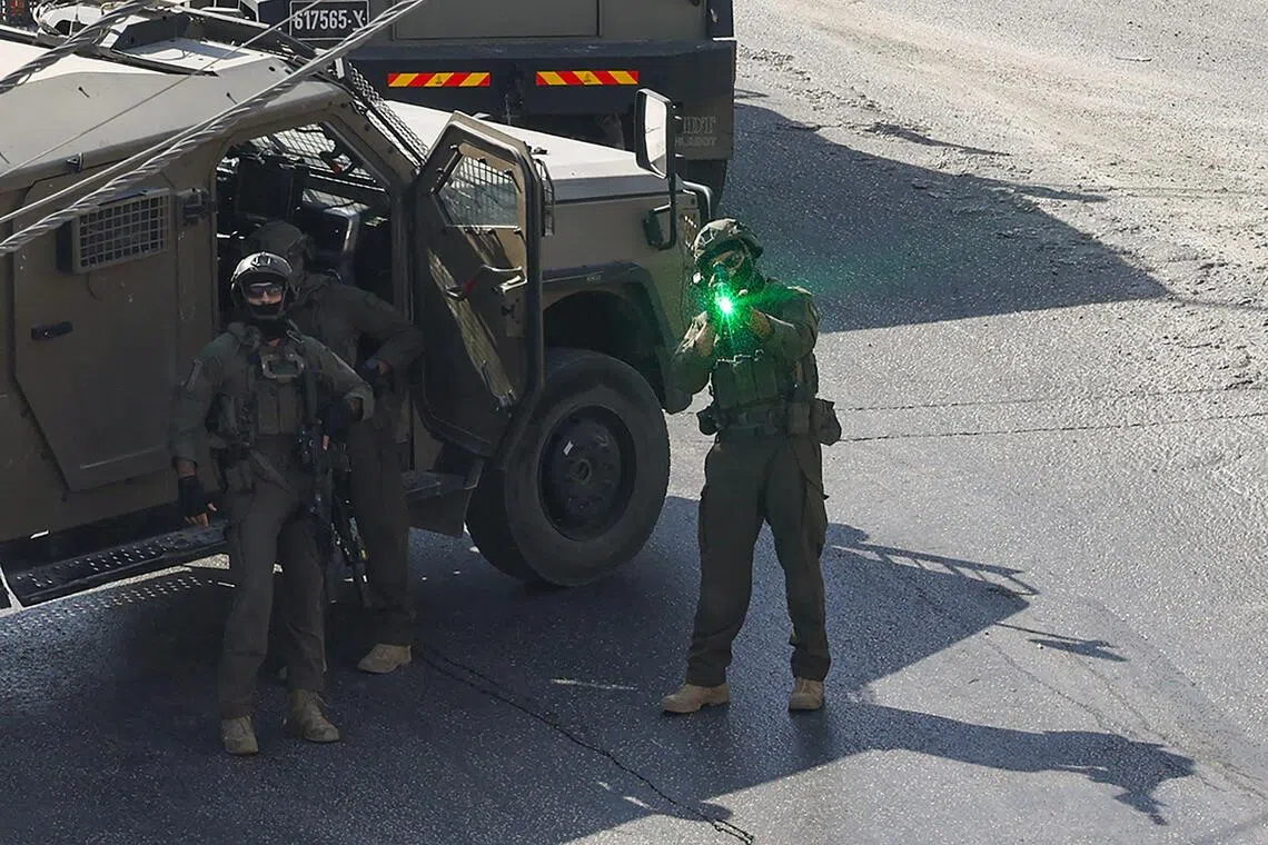 An Israeli soldier aiming his weapon as security forces patrol the Israeli-occupied West Bank city of Hebron, where Palestinian gunmen killed two soldiers, on Oct 23.
