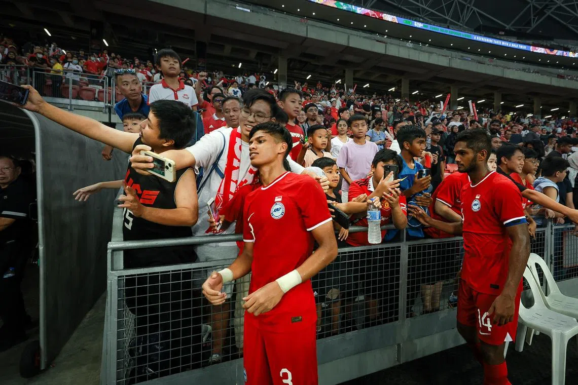 Singapore’s Irfan Najeeb (red, 3, left) and Hariss Harun (red, 14, right) taking pictures with fans after their match with Solomon Island in the international football friendly match at the National Stadium, June 18, 2023.
