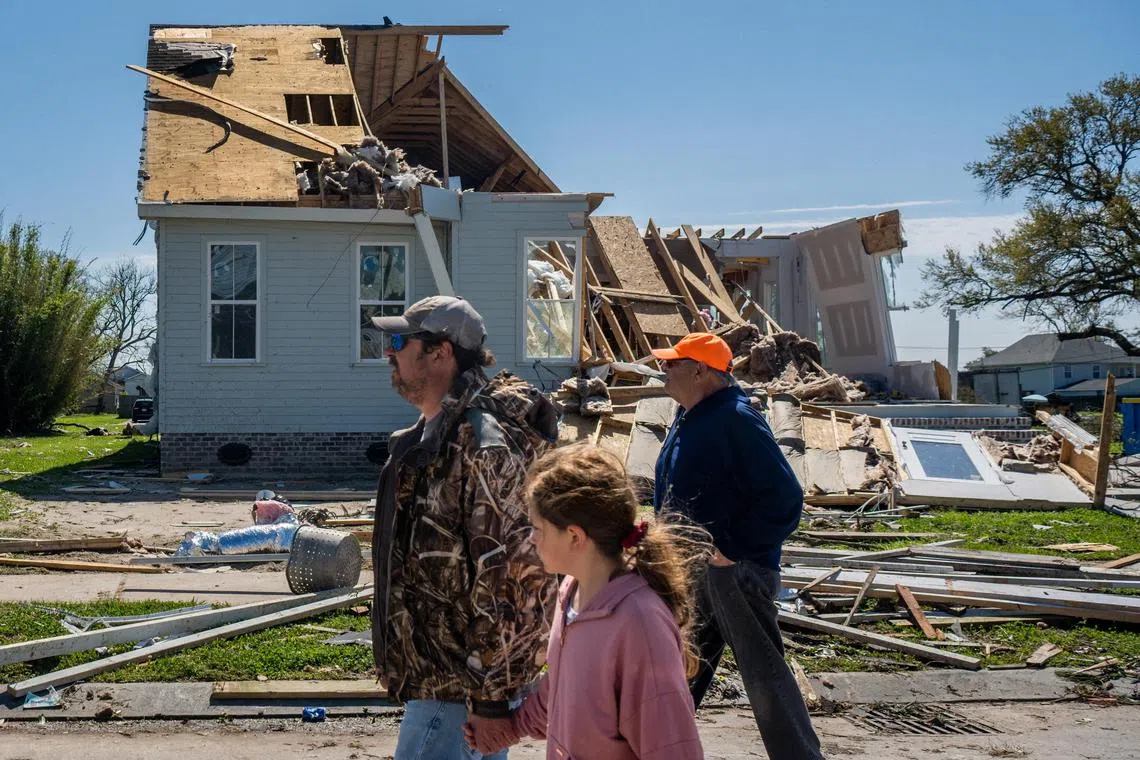 NEW ORLEANS, LOUISIANA - MARCH 23: Richie Majors and his daughter Lilly walk through their tornado-damaged neighborhood on March 23, 2022 in New Orleans, Louisiana. Two tornadoes struck New Orleans last night, leaving several neighborhoods damaged and at least one person dead..   Brandon Bell/Getty Images/AFP (Photo by Brandon Bell / GETTY IMAGES NORTH AMERICA / Getty Images via AFP)