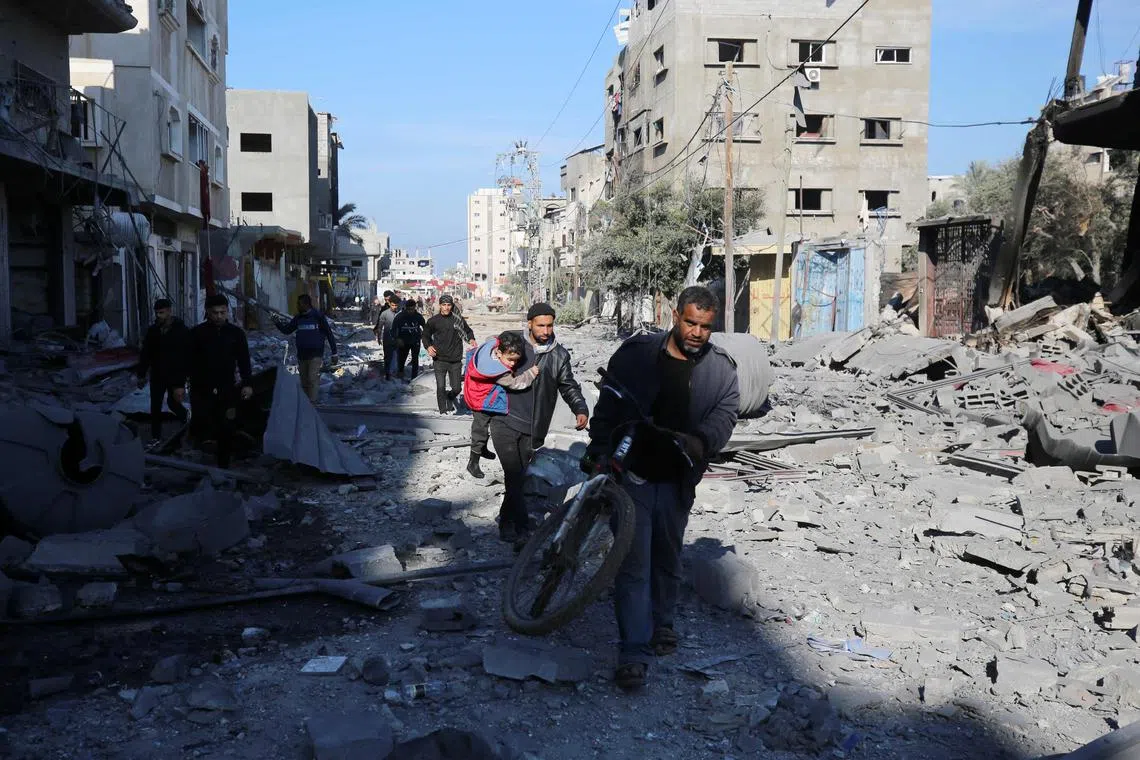 People walking amid rubble in the Al-Maghazi refugee camp in the central Gaza Strip on Jan 16.