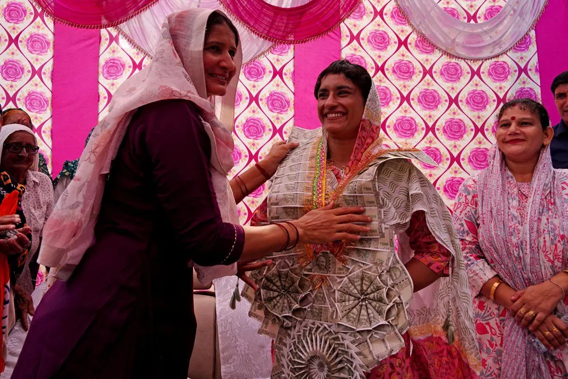 A woman welcoming wrestler turned politician Vinesh Phogat with a garland made of Indian currency notes during her door-to-door election campaign for the upcoming assembly elections in Julana in the northern state of Haryana, India, on Sept 25.