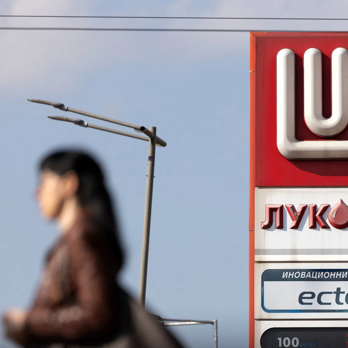 A woman walks near a Lukoil gas station in Sofia, Bulgaria, October 23, 2025.  REUTERS/Stoyan Nenov