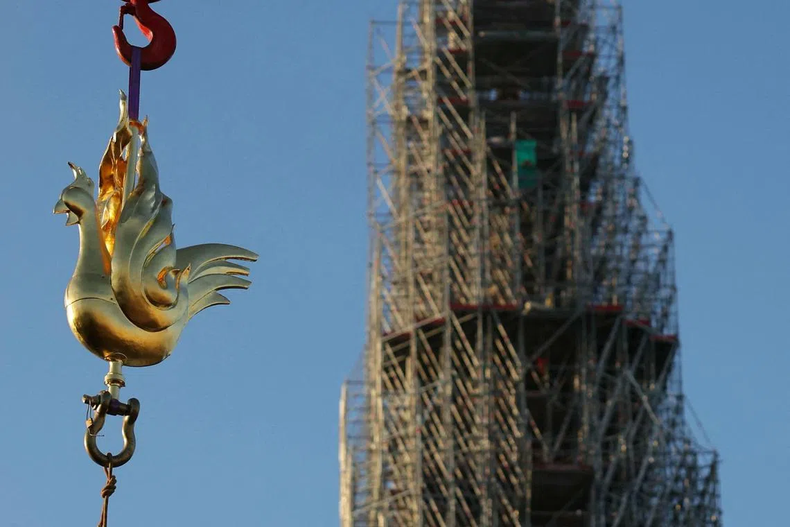 A new golden rooster, containing relics and blessed by Paris' archbishop, is lifted by crane to be installed atop the spire of the reconstructed Notre Dame cathedral.