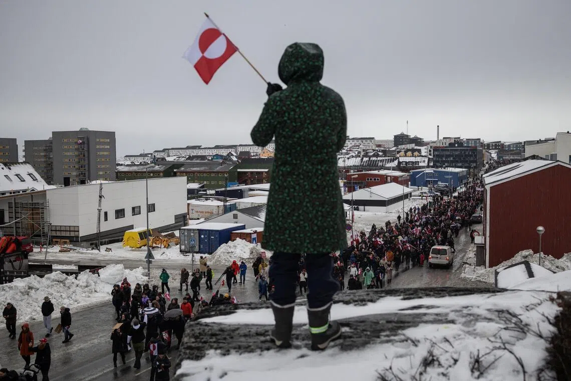 A woman waves a Greenlandic flag as people attend a protest against US President Donald Trump's demand that the Arctic island be ceded to the United States.

