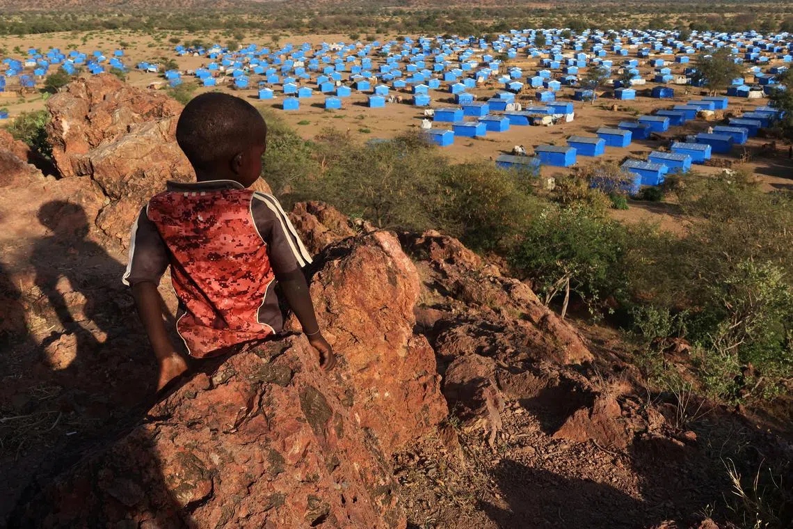 FILE PHOTO: A boy sits atop a hill overlooking a refugee camp near the Chad-Sudan border, November 9, 2023. REUTERS/El Tayeb Siddig/File Photo