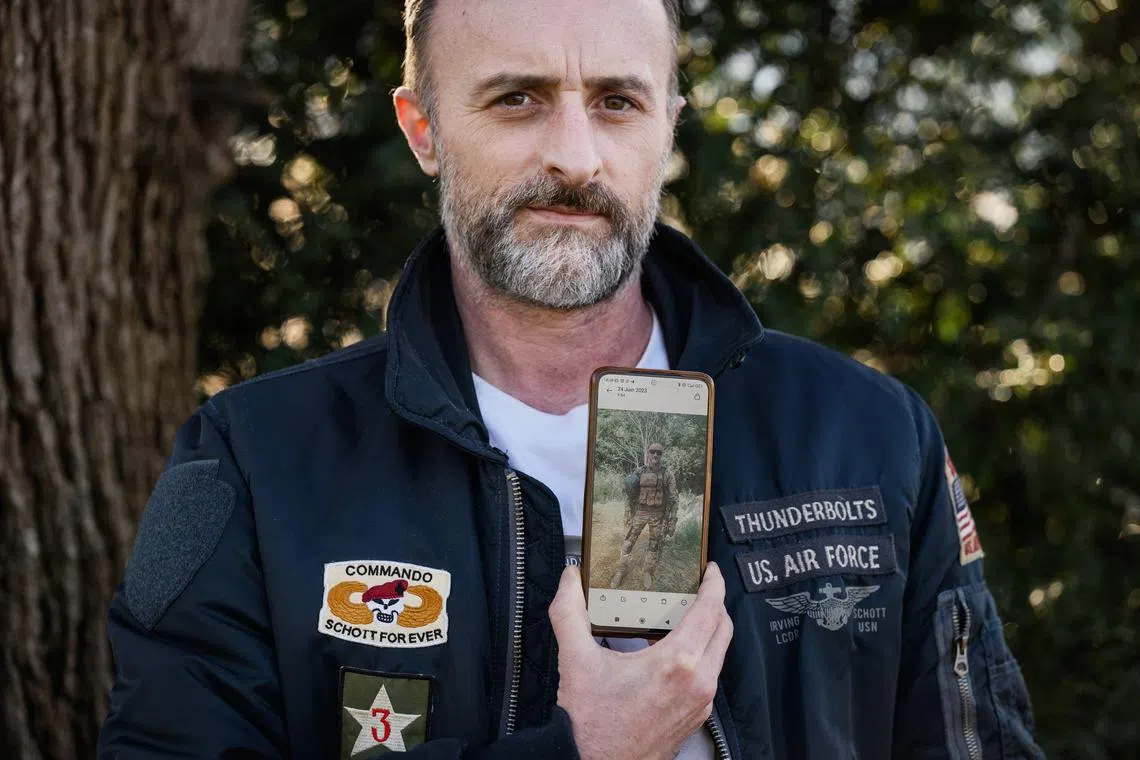 French citizen Beranger Minaud, who says he served in Ukraine's International Legion, shows a photograph of himself in combat gear in Ukraine.