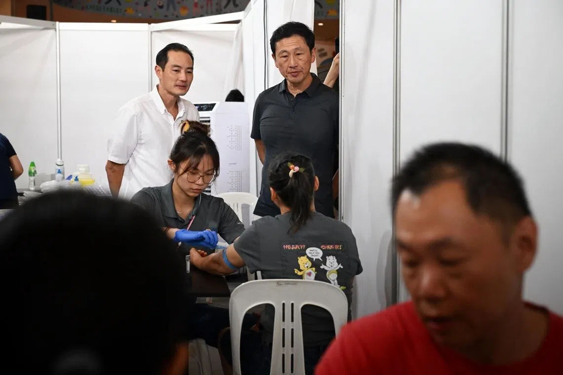 Mr Tan (left) and Mr Ong visiting the tuberculosis screening operations at Heartbeat@Bedok.