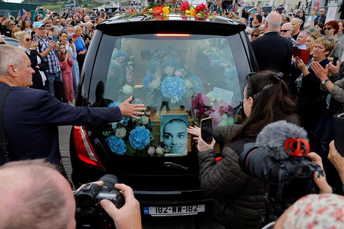 A hearse carrying the coffin of late Irish singer Sinead O'Connor passes by during her funeral procession as fans line the street to say their last goodbye to her, in Bray, Ireland, August 8, 2023. REUTERS/Clodagh Kilcoyne