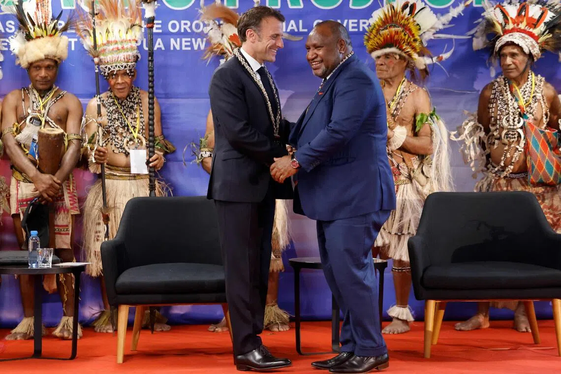 French President Emmanuel Macron (left) is welcomed by Prime Minister of Papua New Guinea James Marape in Port Moresby on July 28, 2023.