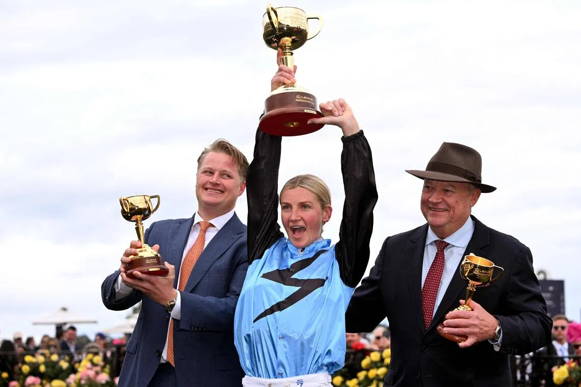 Half Yours Australian jockey Jamie Melham (C) holds the trophy with trainers Calvin McEvoy (L) and Tony McEvoy (R) after her victory in the Melbourne Cup horse race at the Flemington Racecourse in Melbourne on November 4, 2025. Melham became only the second woman jockey to win the Aus$10 million (US$6.5 million) Melbourne Cup on November 4, steering Half Yours to victory in Australia's "race that stops a nation". (Photo by William WEST / AFP) / -- IMAGE RESTRICTED TO EDITORIAL USE - STRICTLY NO COMMERCIAL USE --