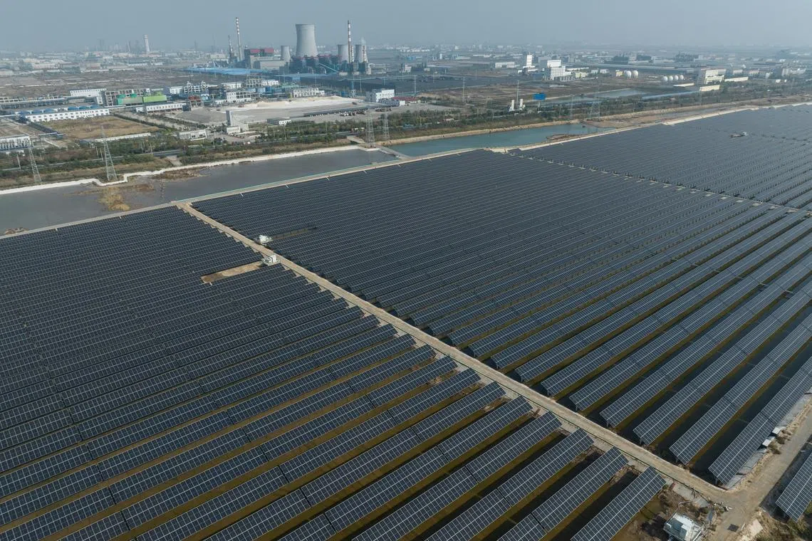 **EMBARGO: No electronic distribution, Web posting or street sales before 12:01 a.m. ET Thursday, Nov. 2, 2023. No exceptions for any reasons. EMBARGO set by source.**Cooling towers of a coal-fired power plant stand near an extensive solar panel farm in Weifang, China on Oct. 23, 2023. China is building as much clean energy capacity over four years as it had promised to build in 10 years, but continues to add coal-fired power plants.(Gilles SabriŽ/The New York Times)