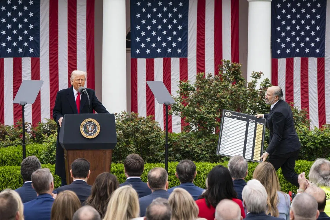 President Donald Trump speaking as Secretary of Commerce Howard Lutnick carries a chart about tariffs in the Rose Garden of the White House, on April 2.