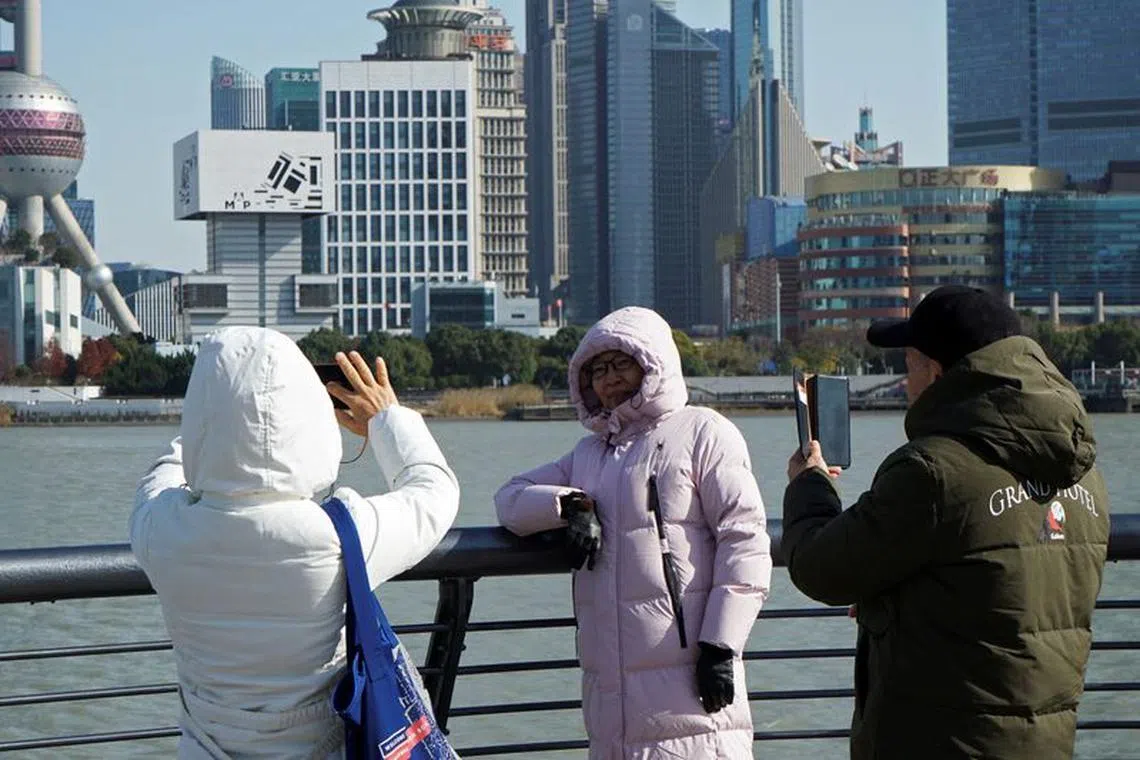 People wearing down jackets take pictures on the Bund on a cold winter day in Shanghai, China December 21, 2023. REUTERS/Nicoco Chan