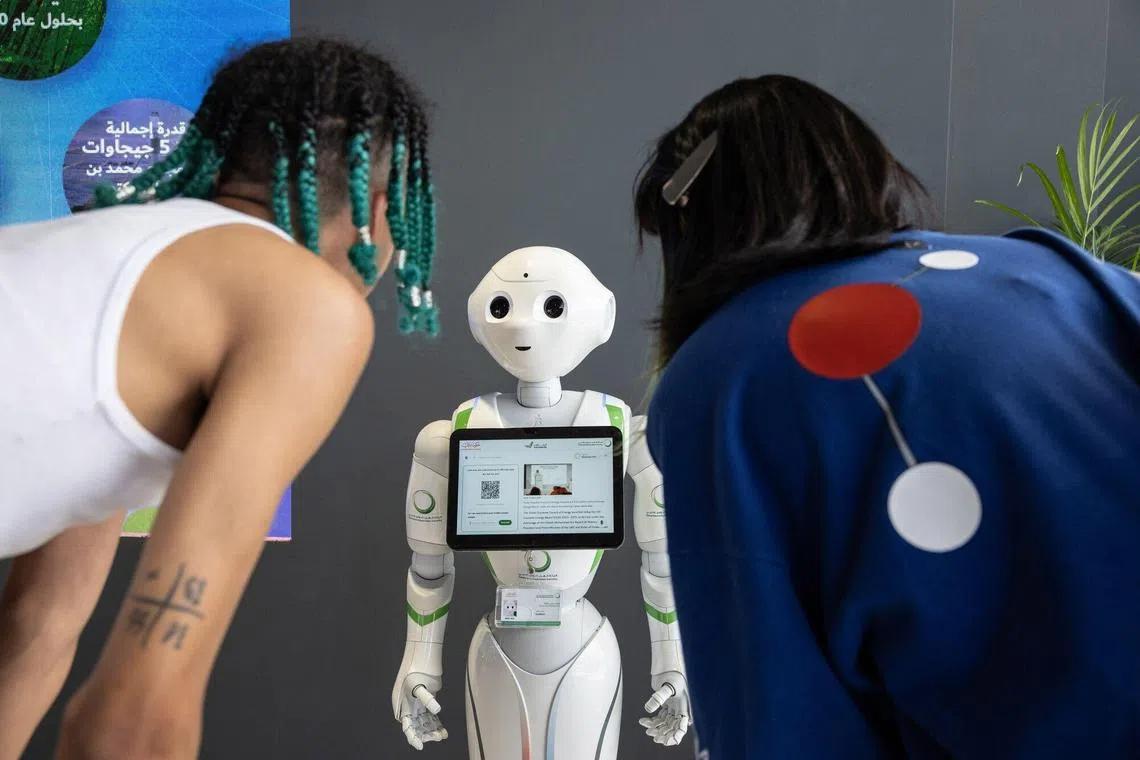 Attendee interact with a SoftBank Group Corp. Pepper humanoid robot inside the Energy Transition hub within the Green Zone on the opening day of the COP28 climate conference at Expo City in Dubai, United Arab Emirates, on Thursday, Nov. 30, 2023. More than 70,000 politicians, diplomats, campaigners, financiers and business leaders will fly to Dubai to talk about arresting the world's slide toward environmental catastrophe. Photographer: Annie Sakkab/Bloomberg