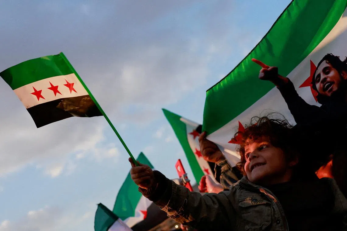 A child holds a flag adopted by the new Syrian rulers, as people gather during a celebration called by Hayat Tahrir al-Sham (HTS)  at the Umayyad Square, after the ousting of Syria's Bashar al-Assad, in Damascus, Syria, December 20, 2024. REUTERS/Ammar Awad/ File Photo