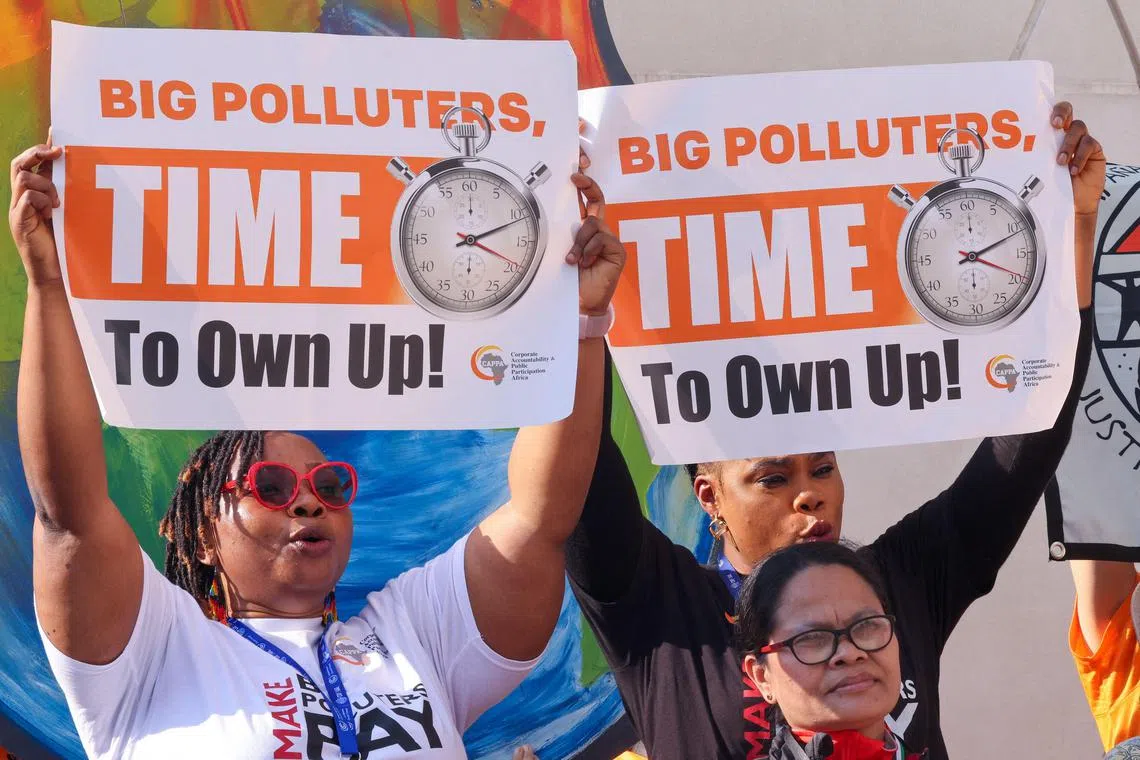 Environmental activists display placards during a demonstration at the venue of the COP28 United Nations climate summit in Dubai on December 5, 2023. The COP28 meeting is being hosted by oil-rich United Arab Emirates, which has made no secret of its plan to include fossil fuel interests and has boosted overall attendance to more than 80,000, making this year's meeting the largest COP. (Photo by Karim SAHIB / AFP)