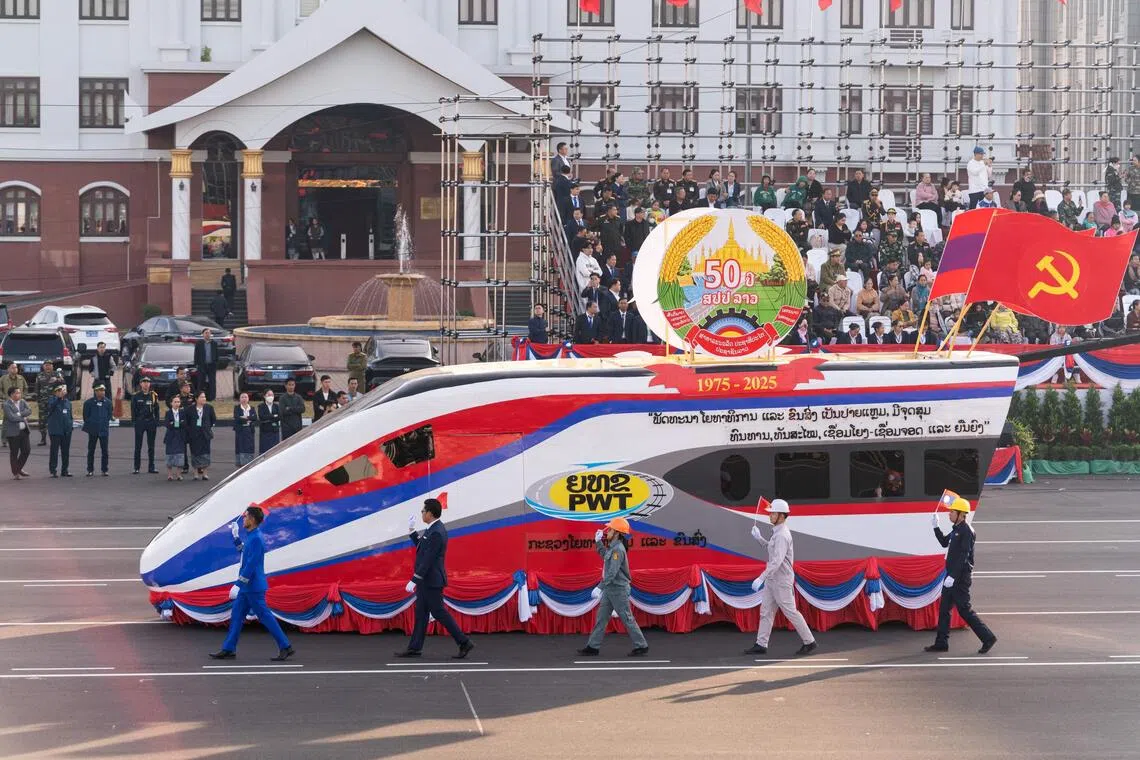 This photo taken on November 28, 2025 shows a high speed train float during a rehearsal for the Lao National Day military parade on December 2 to celebrate 50 years of communist rule on That Luang Esplanade next to the Lao National Assembly in Vientiane. The usually sleepy Lao capital Vientiane has an uncharacteristic buzz, bedecked with flags and T-shirt vendors ahead of commemorations of 50 years of communist rule on December 2, 2025, but for many young people history carries little weight. (Photo by AFP) / To go with 'LAOS-POLITICS-SOCIAL-HISTORY,ADVANCER' by Beatrice Siviero