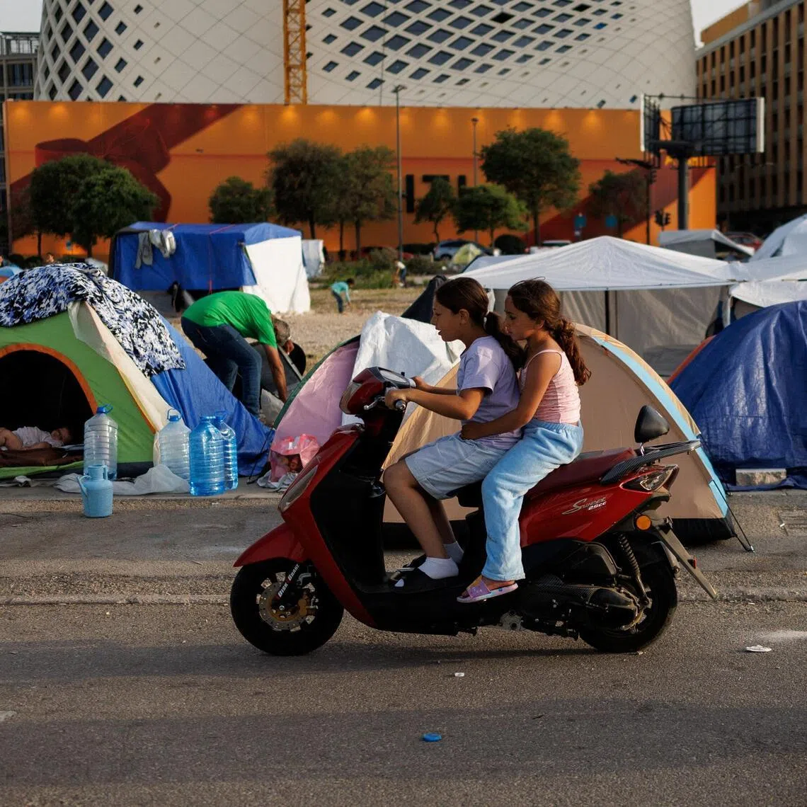 Girls displaced following Israeli evacuation orders ride a scooter at a makeshift encampment in Beirut, Lebanon, on April 15.