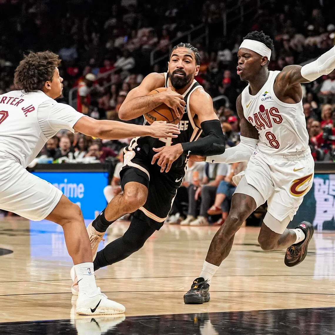 Atlanta Hawks guard Gabe Vincent tries to go between Cleveland Cavaliers guards Craig Porter Jr.  and Dennis Schroder during the first half at State Farm Arena.