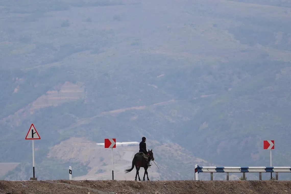A man rides a horse along a road near the Armenia-Azerbaijan border outside the village of Kornidzor, Armenia, September 23, 2023. REUTERS/Irakli Gedenidze/File Photo