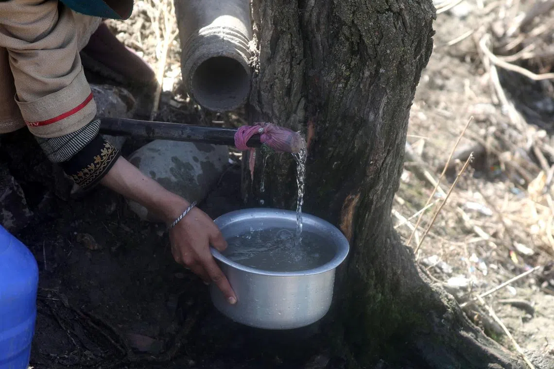 A Kashmiri woman filling her pot from a tap in the village of Pattan, some 22 kilometers north of Srinagar, Kashmir, India, March 18, 2024.