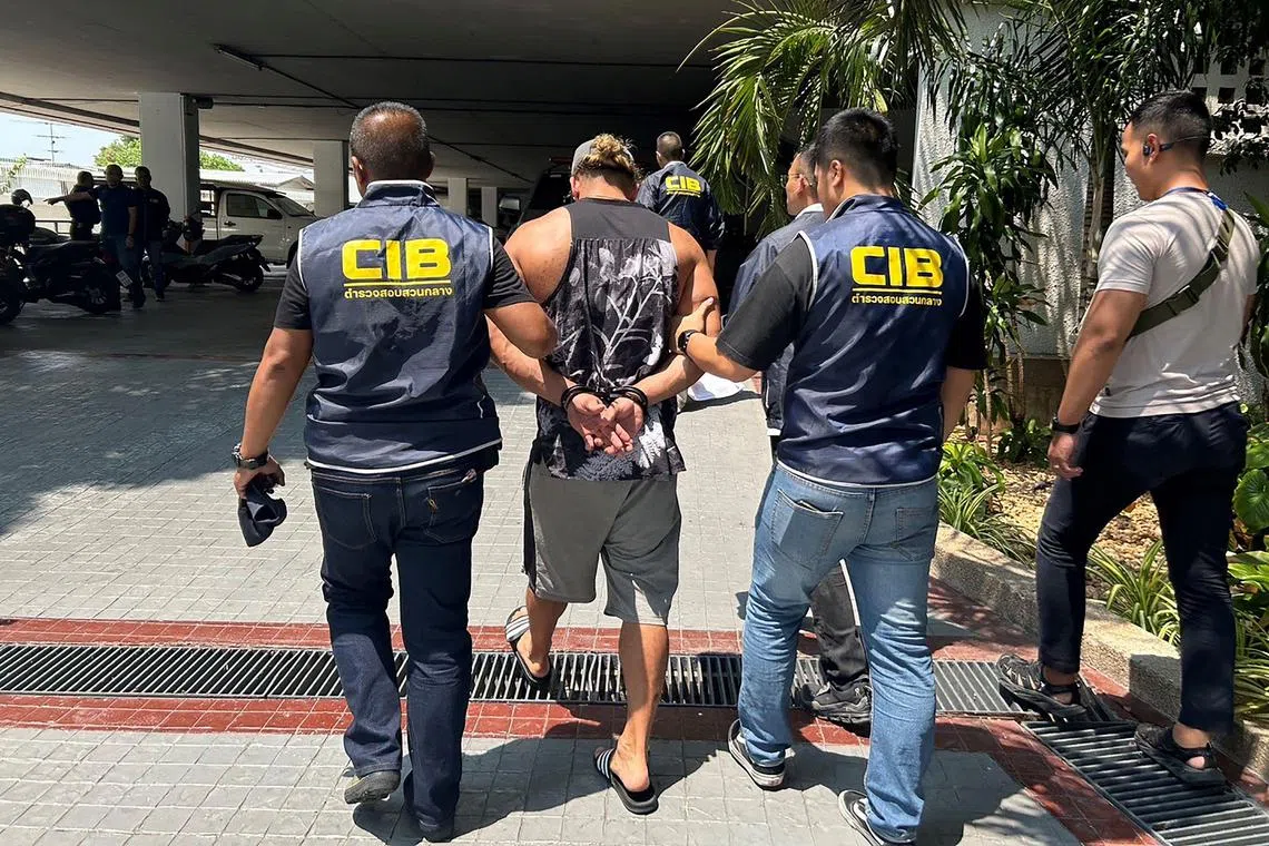 Selva Delano Mudaliar (centre) being led by Thai police officers after being arrested at a condominium building in Bangkok. 