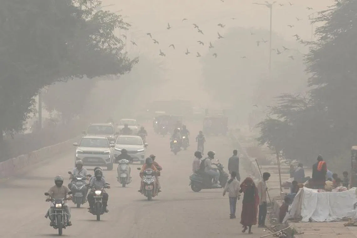 People and vehicles are seen on a road amidst the morning smog in New Delhi, India, November 8, 2023. REUTERS/Anushree Fadnavis