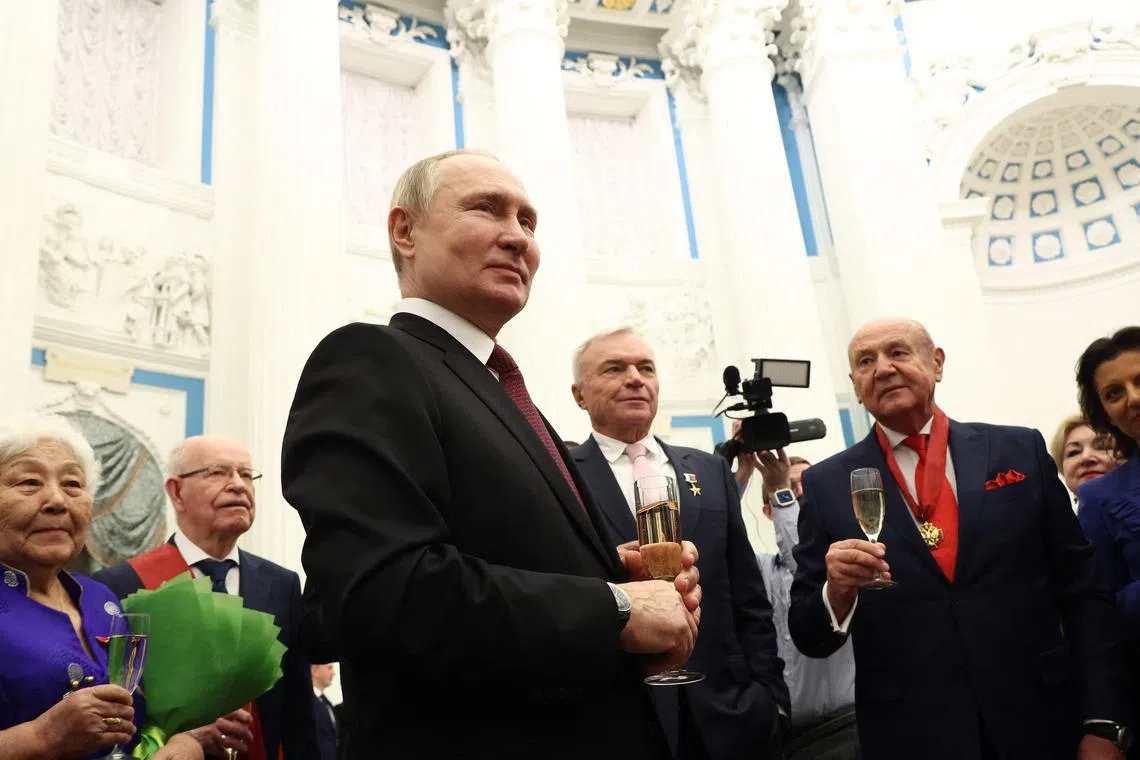 Russian President Vladimir Putin shares a drink with laureats after a state awards ceremony at the Kremlin in Moscow on December 20, 2022. (Photo by Valery SHARIFULIN / SPUTNIK / AFP)