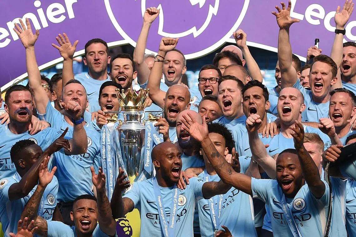 Manchester City’s former manager Pep Guardiola holds the Premier League trophy on the pitch with his players at the Etihad Stadium on May 6, 2018. City has been found guilty of all but one of 115 Premier League charges they face for breaching financial regulations.