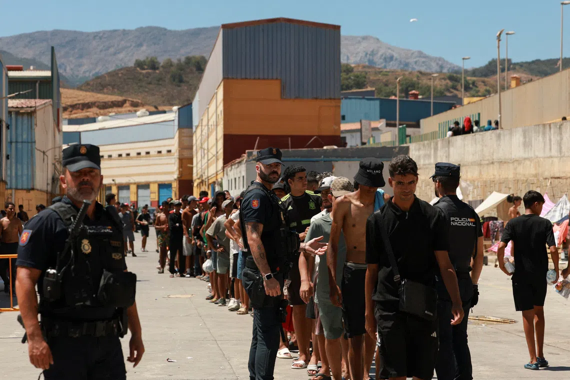 Migrants, some of them minors, queue to receive food staples from local NGO Media Luna Blanca in an industrial area where they are sleeping amid recent mass crossings by migrants on foot and by sea from Morocco into the Spanish territory, in Ceuta, Spain, August 6, 2026. REUTERS/Violeta Santos Moura