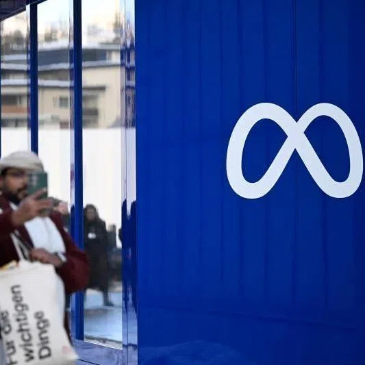 A man uses his phone next to Meta's booth during the World Economic Forum annual meeting in Davos on Jan 19, 2026.