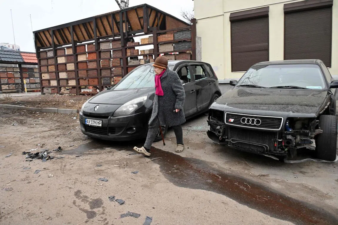 A woman walks by damaged vehicles following a drone attack in Kharkiv on Jan 25.