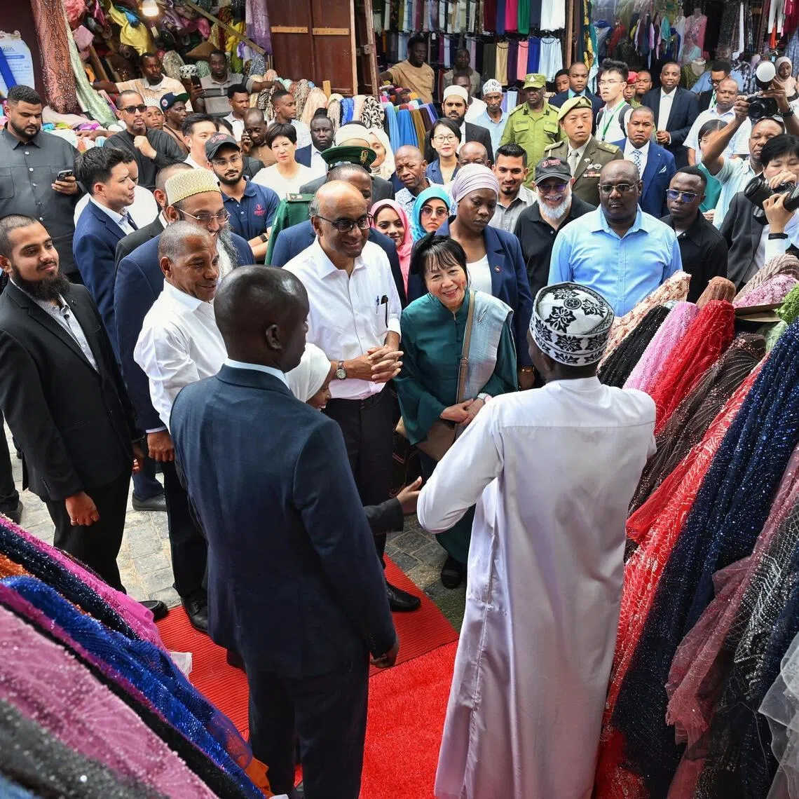 President Tharman Shanmugaratnam and his spouse Jane Ittogi Shanmugaratnam speaking to a shopkeeper selling bridal attire during a visit to the Darajani Souk project at the edge of Stone Town in Zanzibar, Tanzania, on June 10.