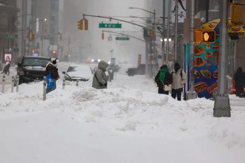 People cross Sixth Avenue in the snow in New York on Jan 25, 2026.